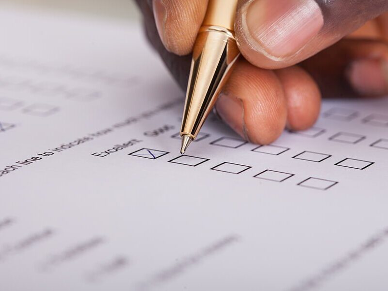 A hand is holding a pen and marking a checkbox on a survey or questionnaire form.